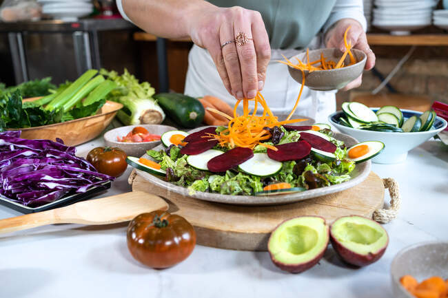 Coltivazione femminile irriconoscibile con carota cruda preparare cibo vegetariano in casa cucina moderna — Foto stock