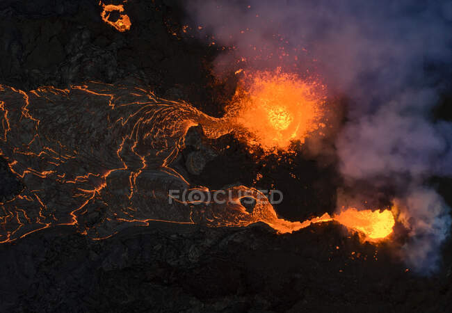 De cima magma faíscas para fora do buraco do vulcão e correr como rios de lava sobre o chão na Islândia — Fotografia de Stock