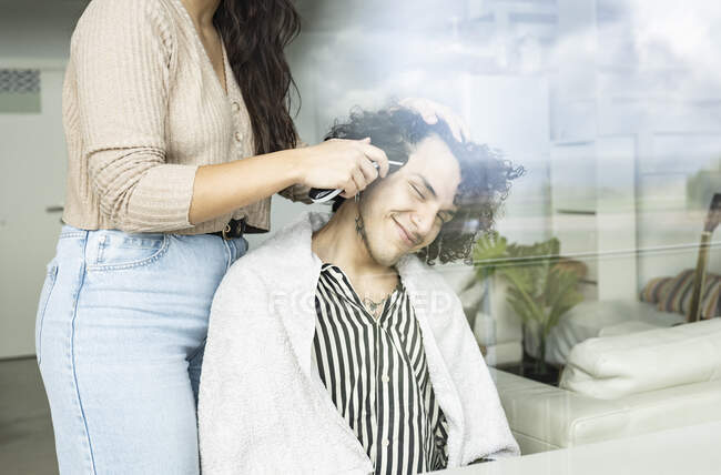 Grâce à la vue en verre de récolte contenu de rasage féminin méconnaissable partenaire masculin avec rasoir électrique dans la maison — Photo de stock
