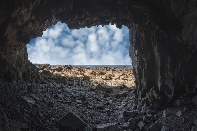Rough rocky cave on stony Campiecho Beach under blue sky on sunny day in Asturias — Stock Photo