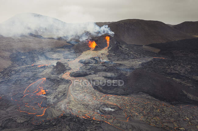 Сверху магма искрится из вулканической ямы и течёт как реки лавы по земле в Исландии. — стоковое фото