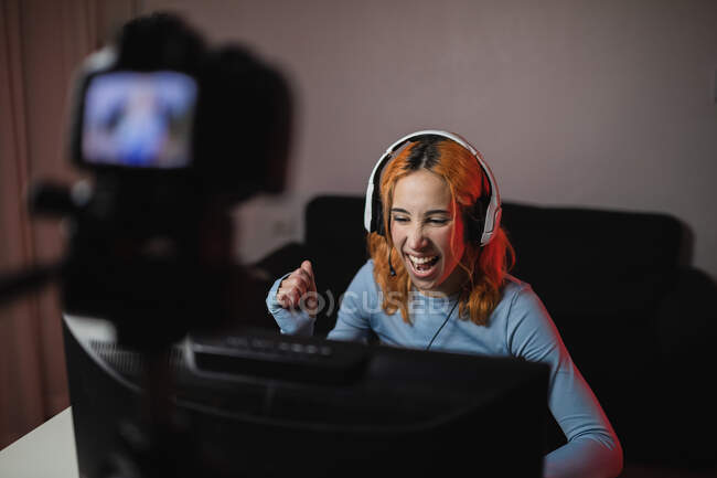 Sorrindo gamer feminino em fones de ouvido gravação de vídeo na câmera profissional para blog de mídia social — Fotografia de Stock