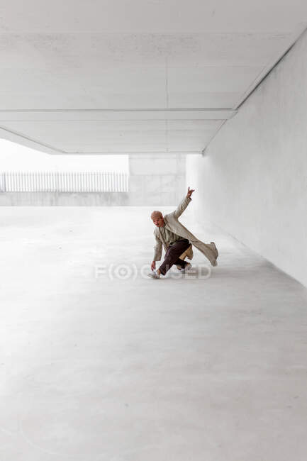 Танцор показывает движение брейк-данса, балансируя на руках и выполняя хмель на бетонном грунте в городской местности — стоковое фото