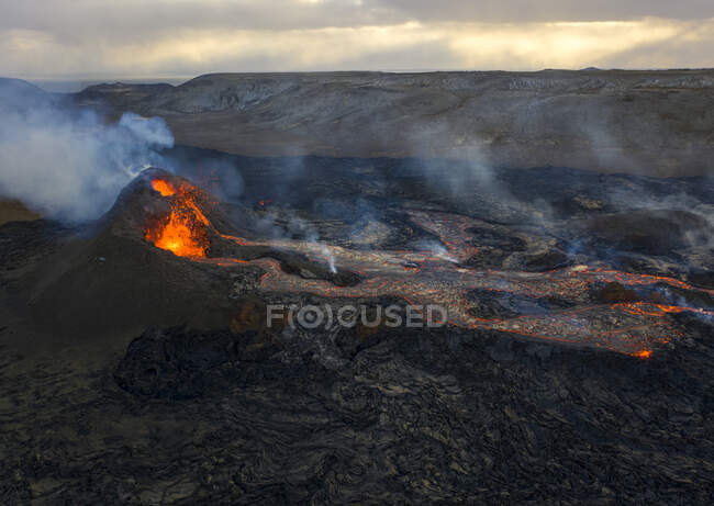 Du haut du magma jaillit du trou volcanique et coule comme des rivières de lave sur le sol en Islande — Photo de stock