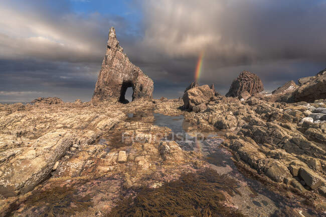 Spettacolare vista dell'arcobaleno colorato sulle formazioni rocciose sulla spiaggia di Campiecho nella giornata di sole nelle Asturie — Foto stock