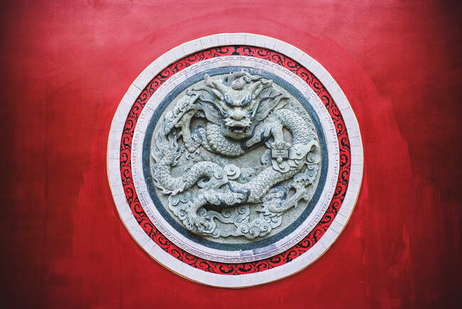 Round shaped ornamental dragon relief on red wall of traditional oriental temple in Yunnan — Stock Photo