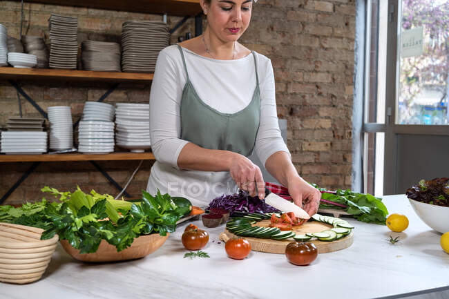 Concentrare il taglio femminile di pomodori freschi maturi tra le fette di zucchine durante il processo di cottura in casa — Foto stock