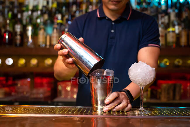 Mains de barman méconnaissable tenant un shaker pour mélanger un cocktail dans le bar — Photo de stock