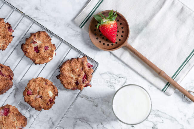 Vue du dessus de délicieux biscuits faits maison avec des fraises placées sur la table avec un verre de lait frais — Photo de stock