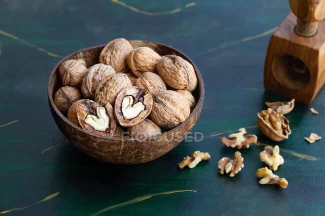 Круглая деревянная чаша, полная хрустящих орехов с сухими неровными орехами на столе — стоковое фото