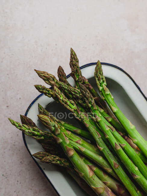 Top view of bunch of fresh green asparagus placed in bowl on table — Stock Photo