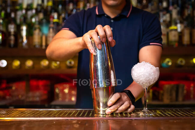 Руки нерозпізнаного бармена, що тримає шейкер для змішування коктейлю в барі. — стокове фото