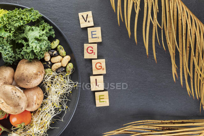 Overhead view of decorative title near plate with cooked potatoes and kale cabbage leaves on nuts and sprouts on gray background — Stock Photo
