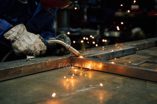 Erntehelfer in Handschuhen und einheitlichen Schweißnähten Metalldetails auf einem Tisch in der Nähe von Konstruktionen in der Fabrik — Stockfoto