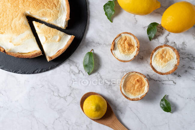 Du dessus de tarte meringue sucrée et citrons frais disposés sur une table en marbre dans la cuisine — Photo de stock