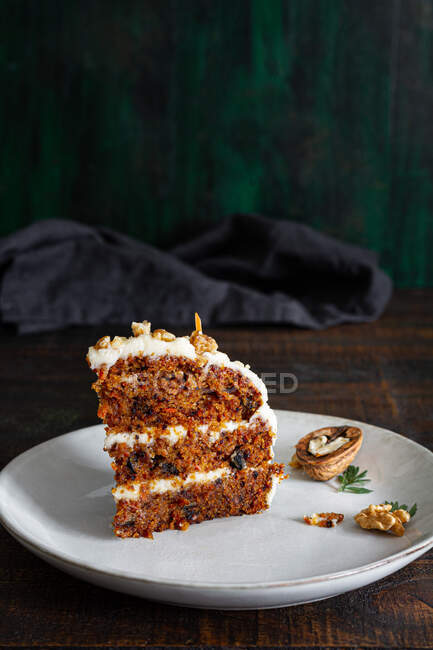 Leckerer Kuchen mit Frischkäse auf Teller serviert mit frischen Karottenscheiben und Walnüssen — Stockfoto