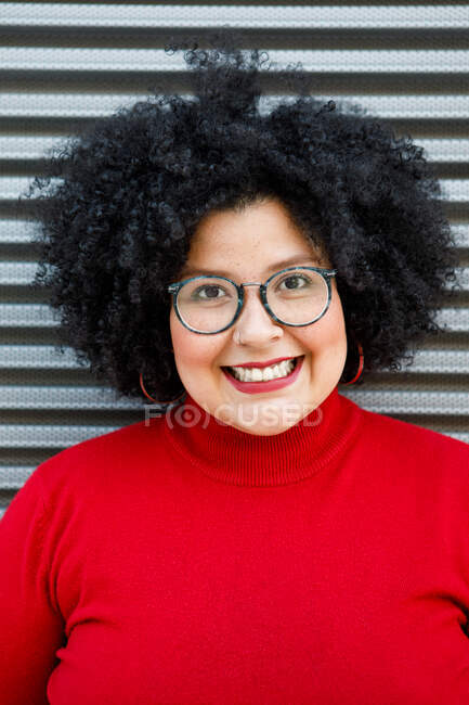 Adulto mulher com sobrepeso em roupas brilhantes e óculos com penteado afro olhando para a câmera — Fotografia de Stock