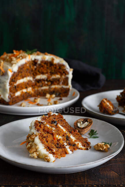 Leckerer Kuchen mit Frischkäse auf Tellern mit frischen Karottenscheiben und Walnüssen — Stockfoto
