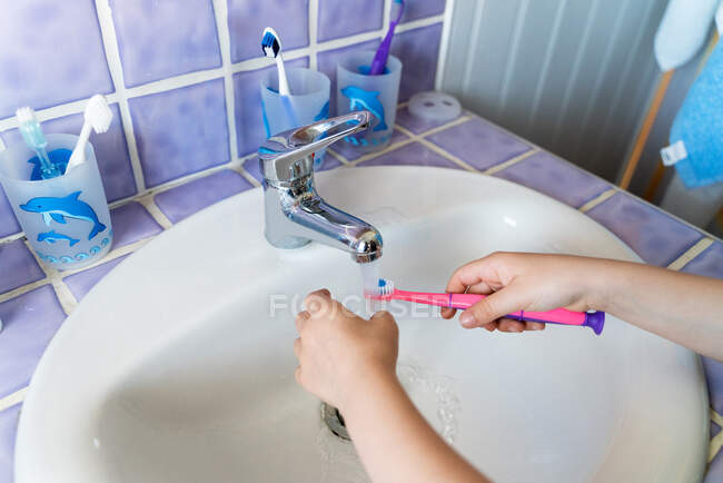 From above anonymous girl washing the toothbrush in the bathroom — Stock Photo