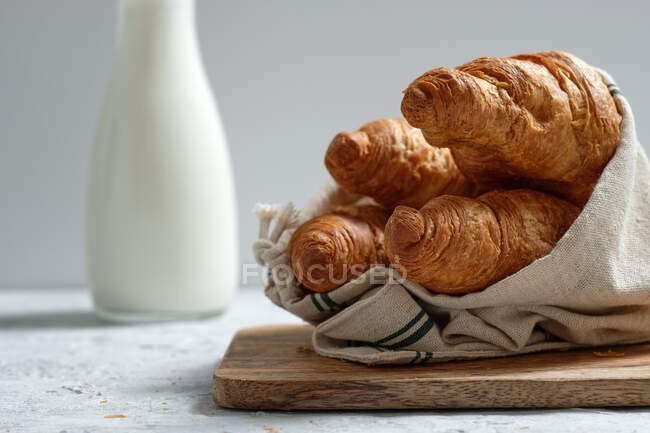 Смачні круасани і пляшка молока, розміщені на столі на сніданок на кухні — стокове фото
