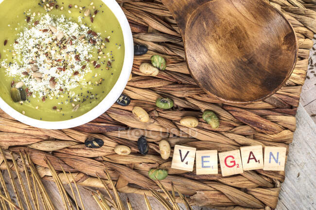 Draufsicht auf appetitliche vegane Sahnesuppe mit zerdrückten Pistazien auf Weidenmatte mit Holzlöffel — Stockfoto