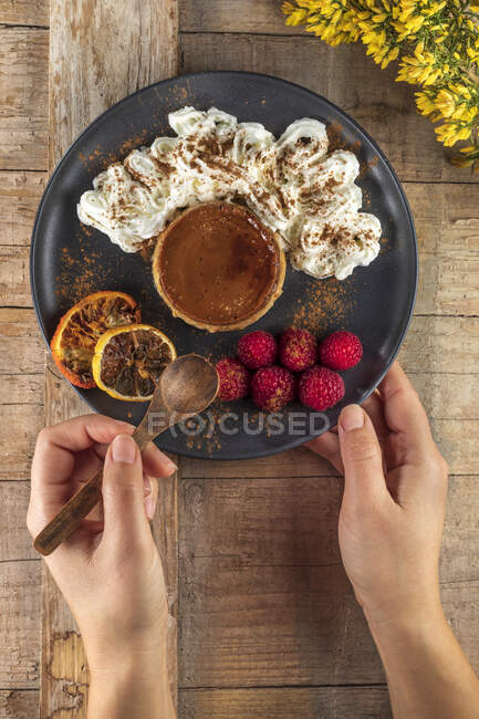 Зверху урожай анонімний кухар з тарілкою смачного запеченого фланця з стиглою малиною та порошком кориці — стокове фото