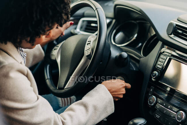 High angle of crop African American female driver starting auto engine with key sitting at steering wheel — Stock Photo