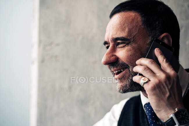 Cultivez heureux entrepreneur hispanique d'âge moyen parlant sur téléphone portable tout en regardant ailleurs dans la journée — Photo de stock