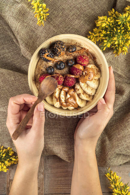 Верхній вигляд невідомого кухаря з банановими скибочками і різні свіжі ягоди з карамельським соусом на сніданок. — стокове фото