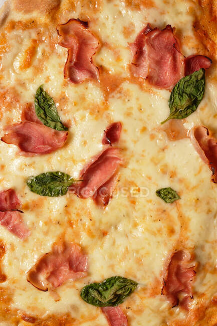 Nahaufnahme von leckerer hausgemachter Pizza mit Basilikum und Schinken auf dem Tisch — Stockfoto