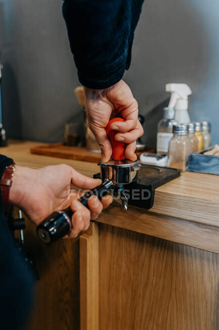 Crop faceless barista standing at table and preparing fresh aromatic coffee while working in cafeteria in daytime — Stock Photo