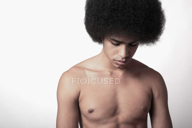 Young confident black man with six pack abs and Afro hairstyle looking down  on white background — self confident, serious - Stock Photo | #467855674