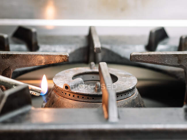Recadrer chef anonyme brûlant cuisinière à gaz avec briquet avant de cuisiner dans la cuisine au restaurant — Photo de stock