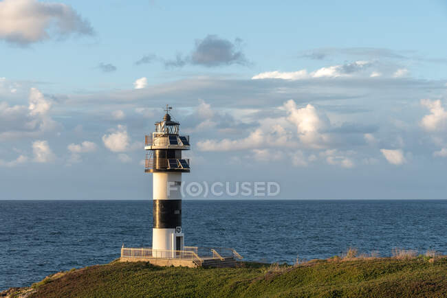Cenário pitoresco da costa gramada com farol colocado perto do oceano azul em Faro Illa Pancha, na Galiza, em Espanha, durante o dia — Fotografia de Stock