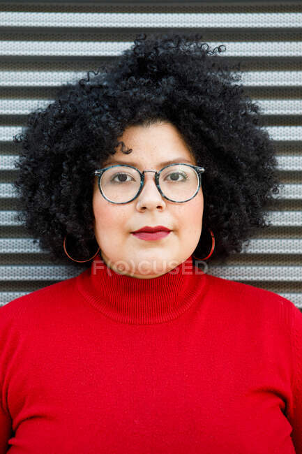 Взрослая женщина с избыточным весом в яркой одежде и очках с прической Афро, смотрящая в камеру — стоковое фото