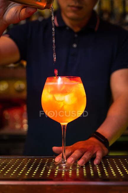 Joven camarero asiático vertiendo agua de soda en pomelo y cóctel de ginebra en el bar - foto de stock