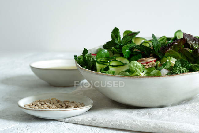 Frischer, gesunder Gemüsesalat in Schüssel, serviert auf dem Tisch mit Olivenöl und Sonnenblumenkernen — Stockfoto