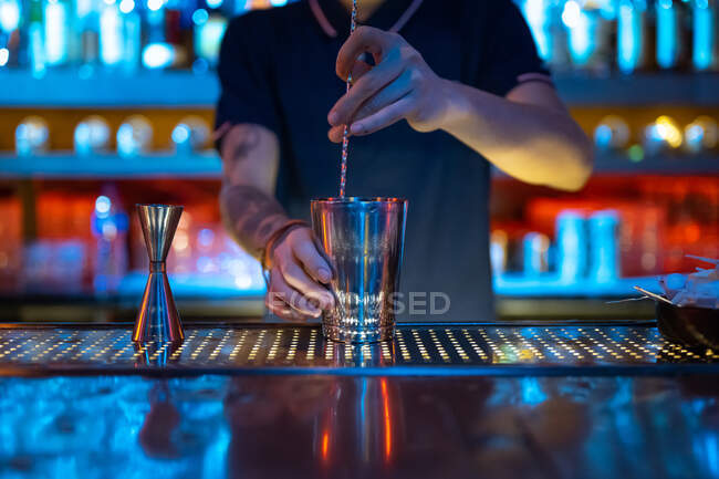 Mãos de barman irreconhecível no trabalho mexendo um coquetel em sua coqueteleira no bar — Fotografia de Stock