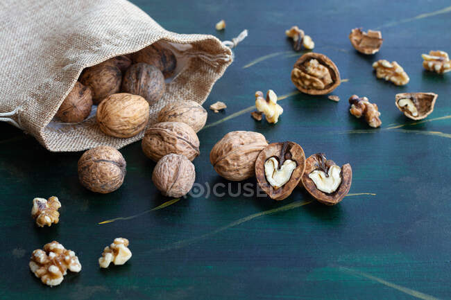 Dall'alto borsa con noci intere e dimezzate con gusci di noce secca e centro a forma di cuore sul tavolo — Foto stock
