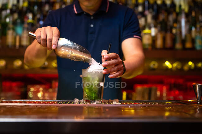 Unbekannter Barkeeper gießt Crushed Ice ins Glas, während er in der Bar einen Mojito-Cocktail zubereitet — Stockfoto