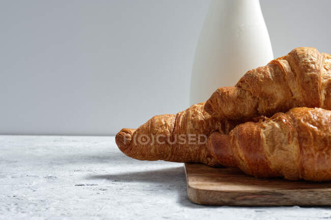 Смачні круасани і пляшка молока, розміщені на столі на сніданок на кухні — стокове фото