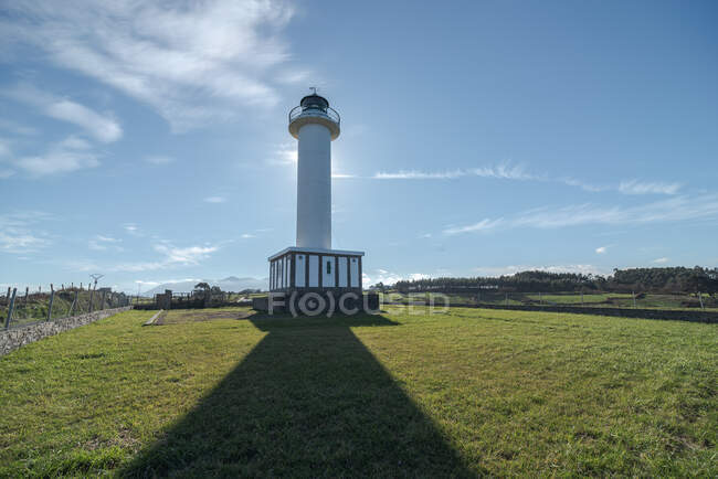 Shadow leading to white lighthouse placed in Faro de Lastres in Asturias in Spain under cloudless blue sky in daytime — Stock Photo