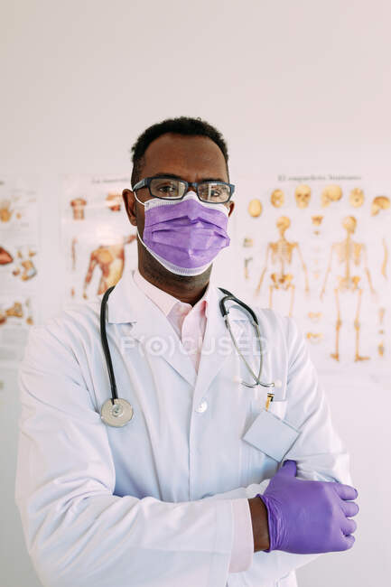 Афроамериканський лікар з стетоскопом у формі та окулярах, який дивиться на камеру в лікарні. — стокове фото