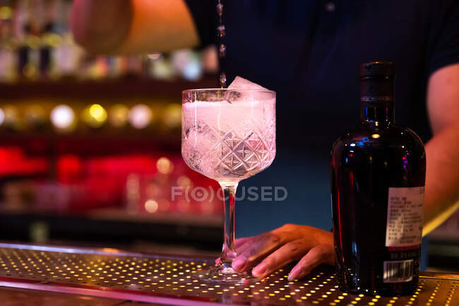 Junger asiatischer Barkeeper gießt Tonic Water ins Glas, um in der Bar einen Gin Tonic Cocktail zuzubereiten — Stockfoto