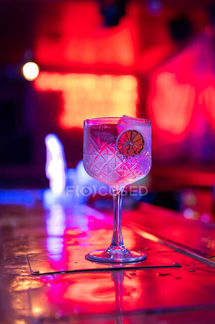 Cóctel gin tonic bien elaborado decorado con fresas y tobogán de limón seco en el bar - foto de stock