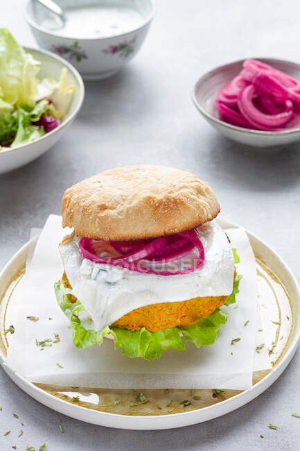 Appetizing homemade veggie curry and mango chickpea burger with fresh lettuce and picked red onion and soy cheese served with yogurt sauce — Stock Photo