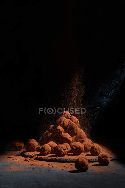 Un mucchio di deliziosi tartufi di cioccolato a forma di palle impilate sul tavolo su sfondo scuro in studio — Foto stock