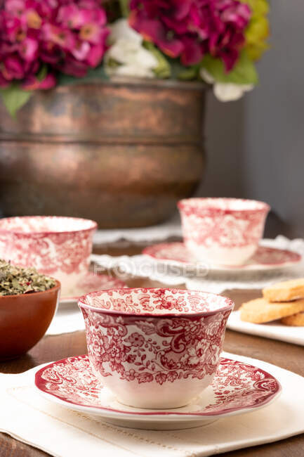 Tasses décoratives en céramique servies sur table avec des fleurs pour le thé dans une chambre confortable à la maison — Photo de stock