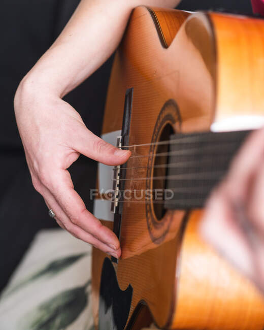 Músico de cosecha en ropa casual tocando la guitarra en la sala de luz en casa durante el día - foto de stock