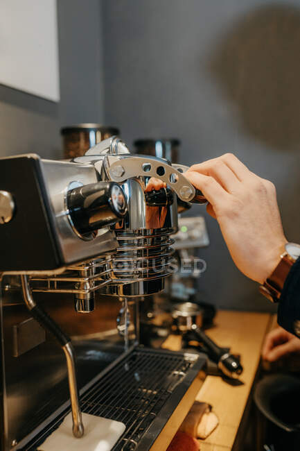 Cultiver barista anonyme en utilisant mousseur de lait tout en nettoyant la machine à café à la cafétéria pendant le travail de jour — Photo de stock